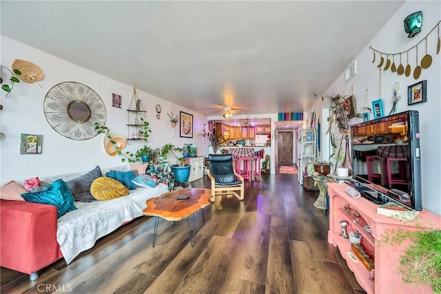 living room with visible vents, dark wood-type flooring, and a ceiling fan