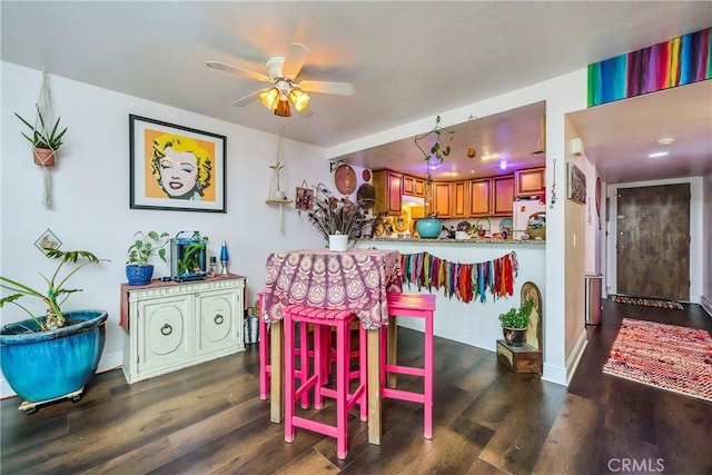 dining space featuring a ceiling fan, baseboards, and wood finished floors