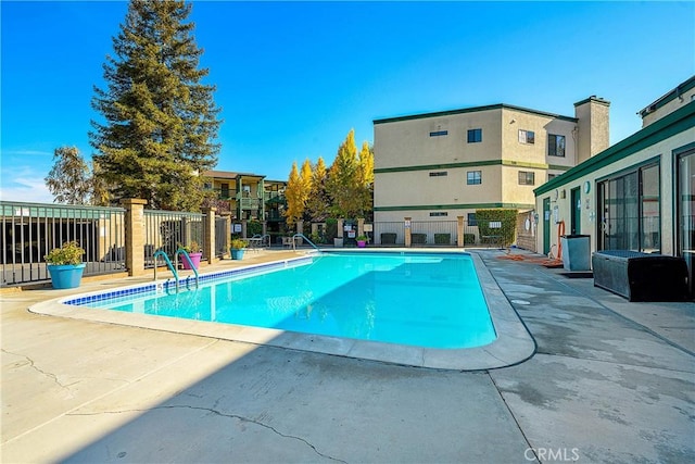 pool with a patio area and fence