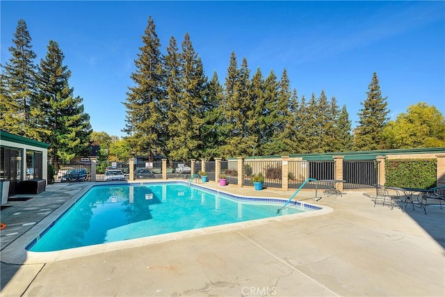 community pool with a patio area and fence