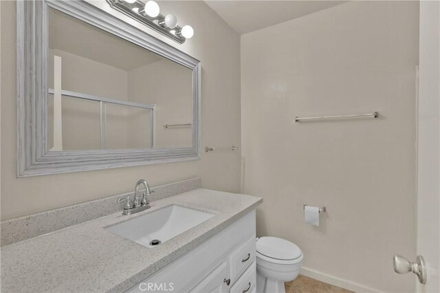 bathroom with vanity, baseboards, a stall shower, tile patterned flooring, and toilet