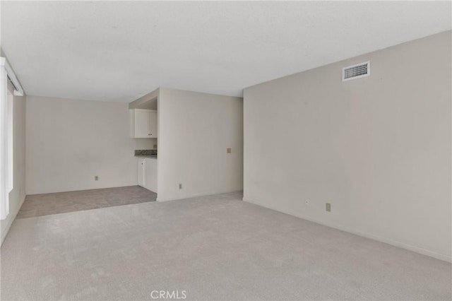 unfurnished living room featuring visible vents and light carpet