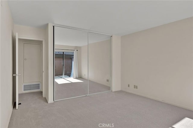 unfurnished bedroom featuring visible vents, carpet, and a closet