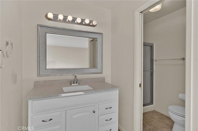 full bath featuring tile patterned flooring, baseboards, toilet, a stall shower, and vanity