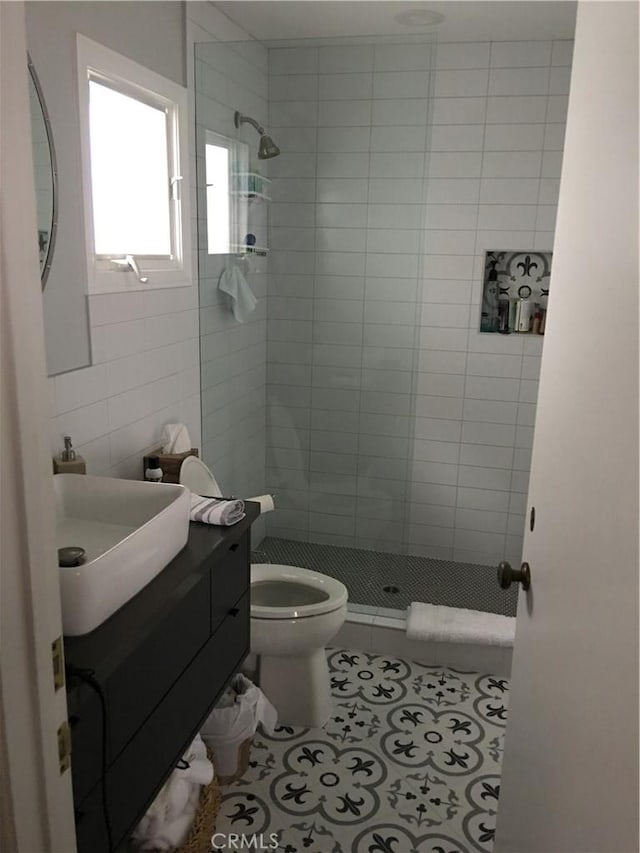 bathroom with tile patterned flooring, a tile shower, vanity, and tile walls