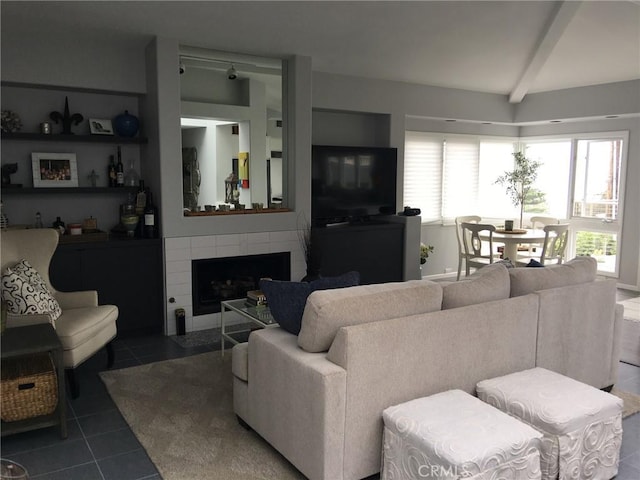 tiled living area with a tile fireplace and beamed ceiling