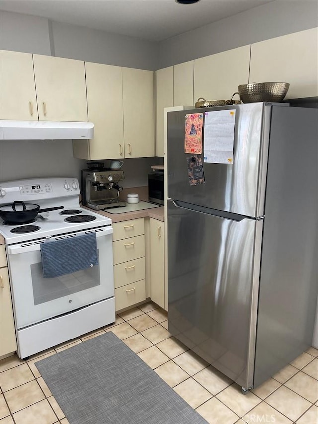 kitchen featuring white range with electric stovetop, freestanding refrigerator, under cabinet range hood, light countertops, and cream cabinetry