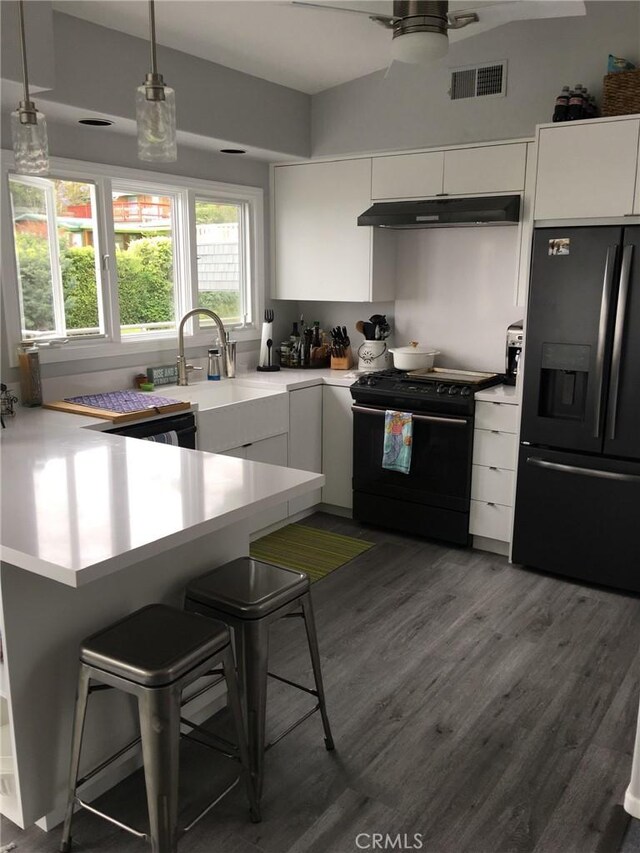 kitchen with black appliances, under cabinet range hood, white cabinetry, a peninsula, and light countertops
