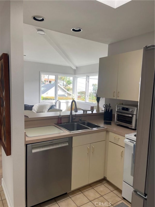 kitchen with appliances with stainless steel finishes, light tile patterned floors, light countertops, cream cabinets, and recessed lighting