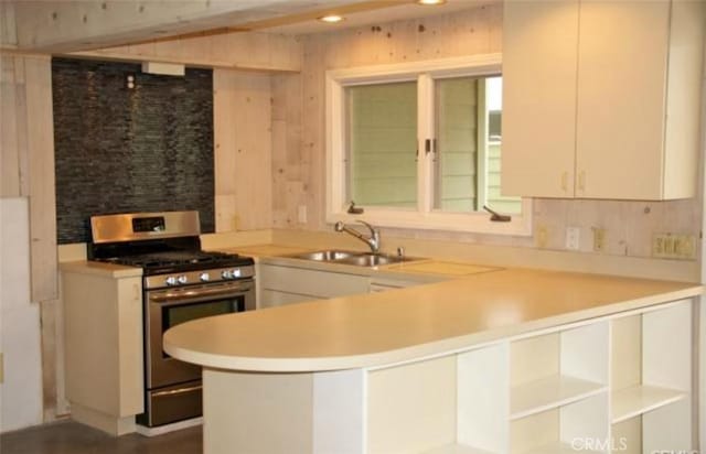 kitchen with gas range, light countertops, a peninsula, white cabinetry, and tasteful backsplash