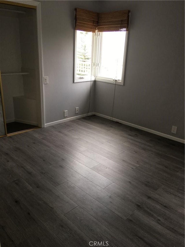unfurnished bedroom with dark wood finished floors and baseboards