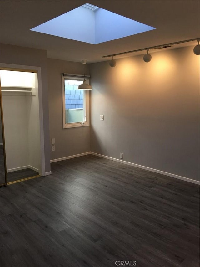 unfurnished bedroom with rail lighting, dark wood-style floors, and a closet