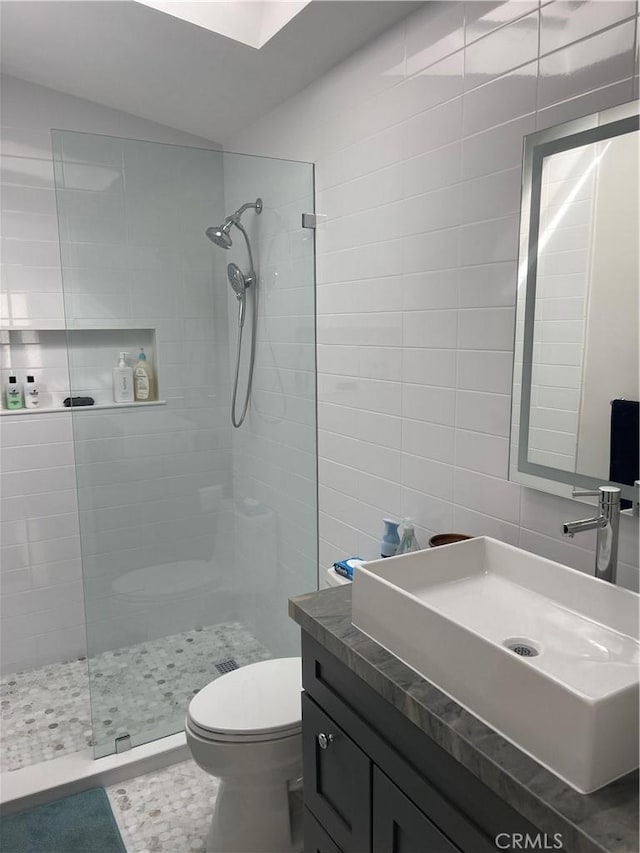 full bath featuring walk in shower, vanity, tile walls, and lofted ceiling