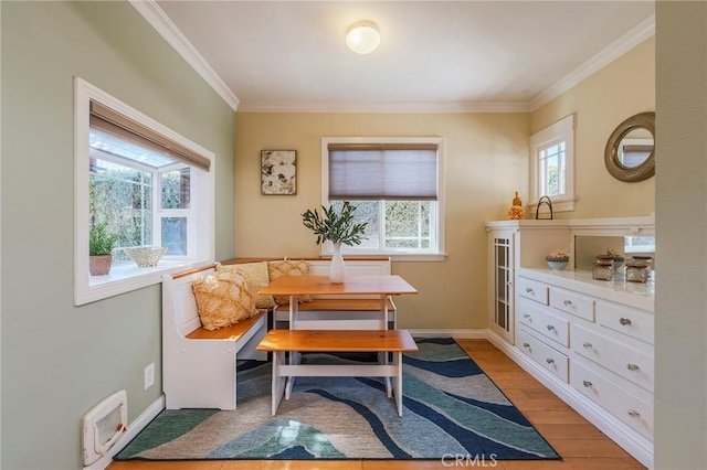 dining space featuring light wood finished floors, baseboards, visible vents, breakfast area, and crown molding