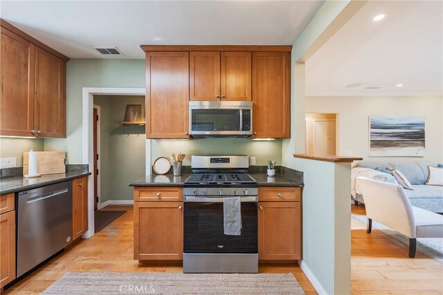 kitchen with stainless steel appliances, light wood-type flooring, brown cabinetry, and visible vents