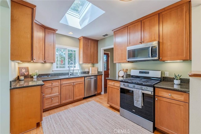 kitchen featuring recessed lighting, a skylight, a sink, appliances with stainless steel finishes, and brown cabinetry