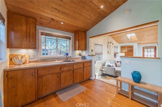 kitchen featuring vaulted ceiling with skylight, brown cabinetry, wood ceiling, open floor plan, and light wood-style floors