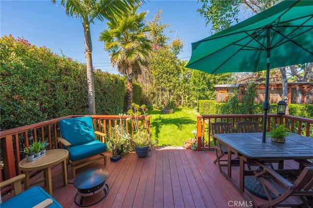 wooden deck with a lawn and outdoor dining space