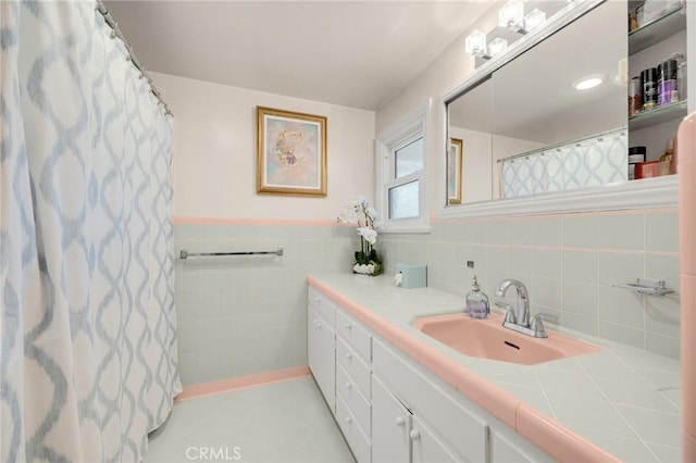 bathroom with a shower with shower curtain, a wainscoted wall, tile walls, and vanity