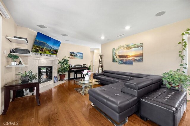 living room with visible vents, a fireplace, and wood finished floors