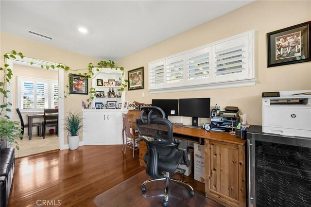 office space with visible vents, wood finished floors, and beverage cooler