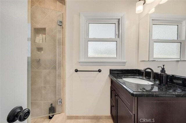 bathroom featuring a stall shower, vanity, and baseboards