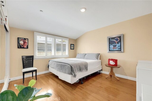 bedroom featuring vaulted ceiling, baseboards, and light wood finished floors