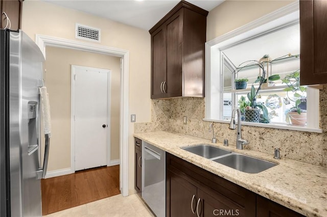 kitchen with tasteful backsplash, visible vents, dark brown cabinets, stainless steel appliances, and a sink