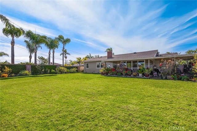 back of property featuring a yard, fence, and a chimney