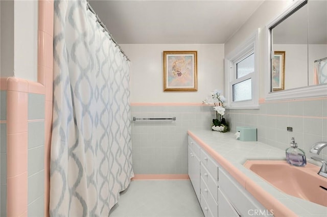 bathroom with vanity, tile walls, curtained shower, and a wainscoted wall