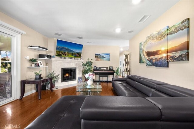 living area with a fireplace, wood finished floors, and visible vents