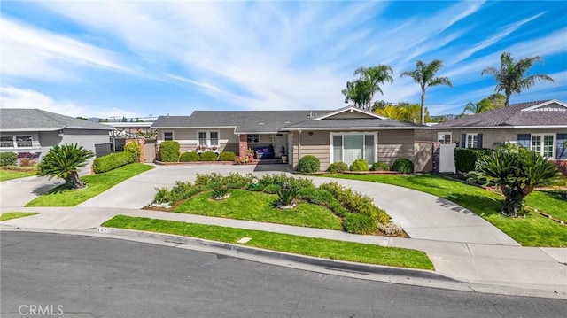 single story home with a front lawn, driveway, and fence