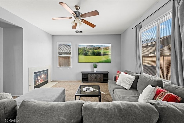 carpeted living room featuring a fireplace with flush hearth, a wealth of natural light, visible vents, and a ceiling fan