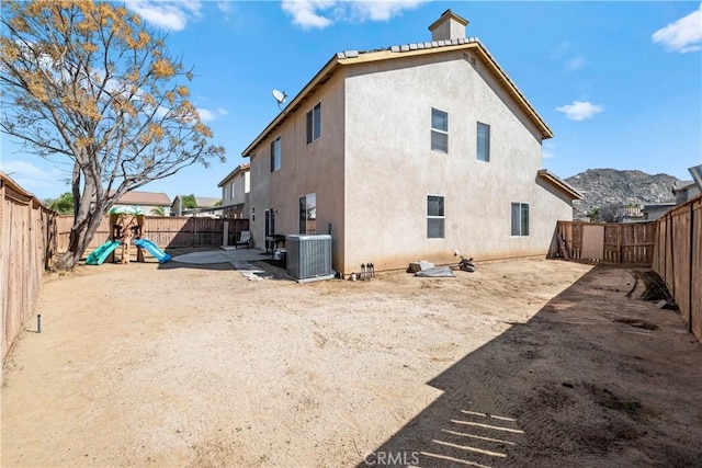 back of house featuring stucco siding, a fenced backyard, central AC unit, and a patio