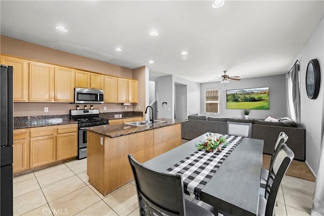 kitchen featuring light brown cabinetry, appliances with stainless steel finishes, open floor plan, a kitchen island with sink, and a sink