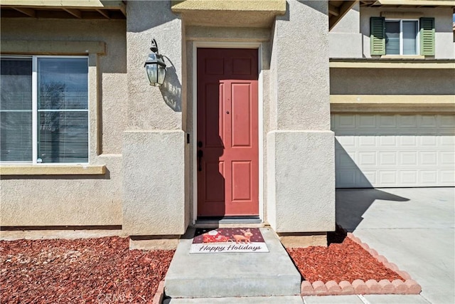 doorway to property featuring an attached garage and stucco siding