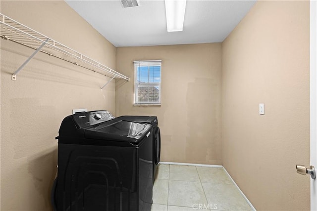 laundry area featuring washer and clothes dryer, visible vents, light tile patterned flooring, laundry area, and baseboards