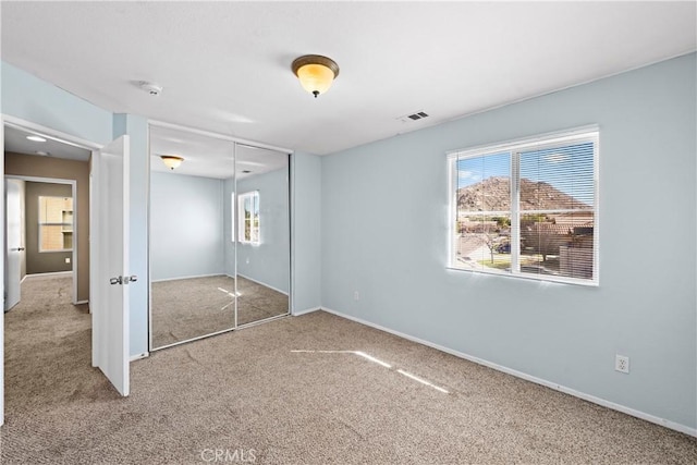 unfurnished bedroom featuring baseboards, a closet, visible vents, and carpet flooring