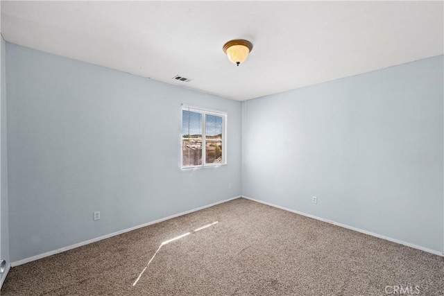 empty room with carpet floors, visible vents, and baseboards