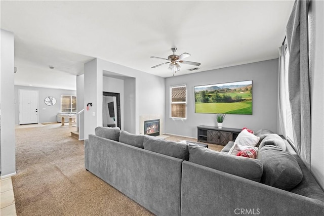 living room with ceiling fan, light carpet, a fireplace, visible vents, and baseboards