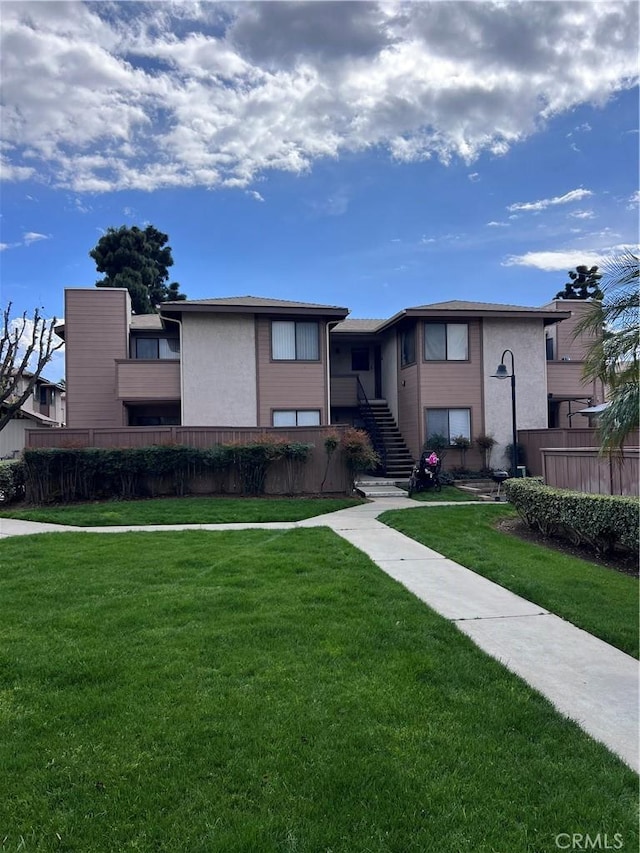 view of front of house featuring stairway, fence, and a front lawn