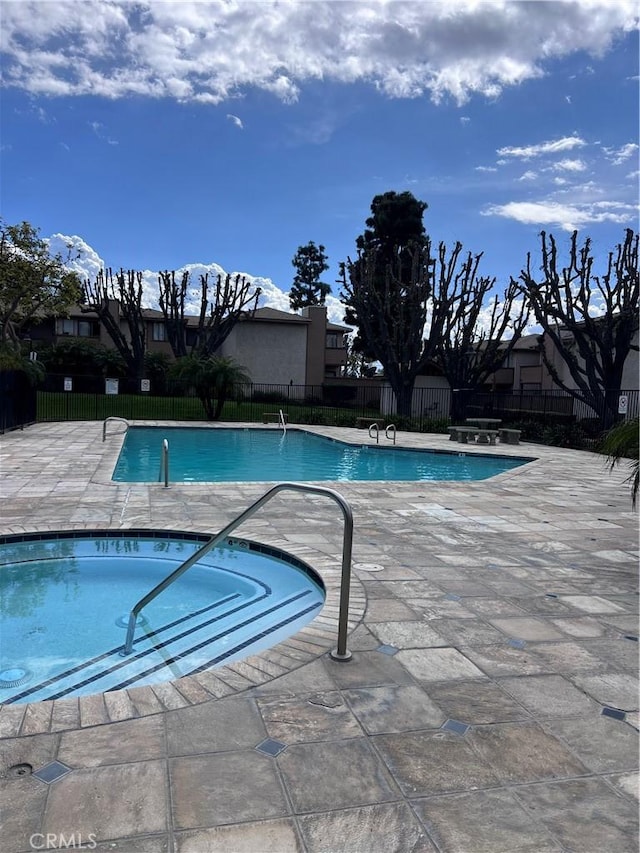 community pool with a patio area and fence