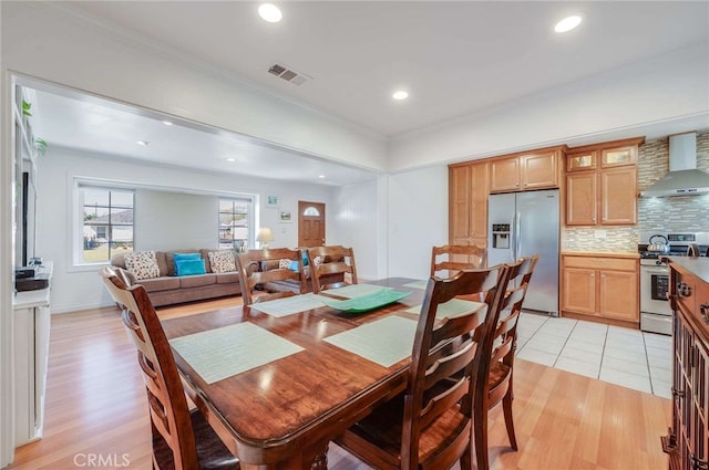 dining room featuring crown molding, light wood-type flooring, visible vents, and recessed lighting