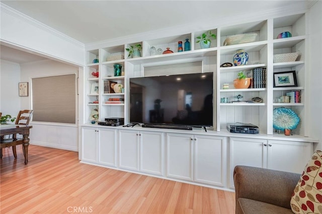 living room with light wood-style flooring, built in shelves, and crown molding