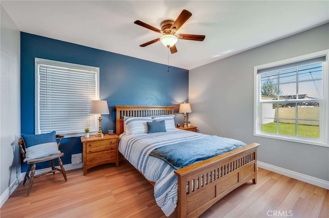 bedroom with light wood-style floors, baseboards, and a ceiling fan