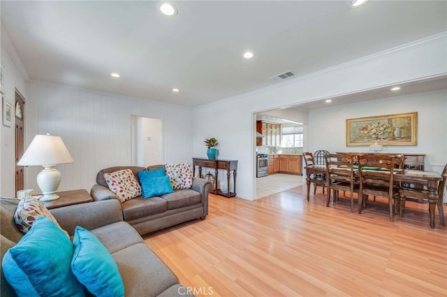 living room with ornamental molding, light wood-type flooring, visible vents, and recessed lighting