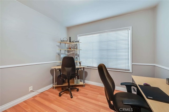 office space with baseboards, vaulted ceiling, and light wood finished floors