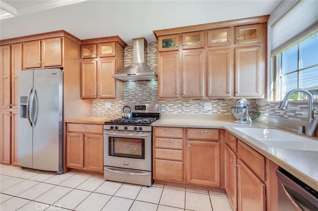 kitchen with stainless steel appliances, wall chimney exhaust hood, a sink, and light countertops