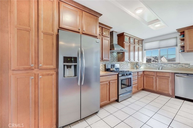 kitchen featuring stainless steel appliances, light countertops, decorative backsplash, a sink, and wall chimney range hood