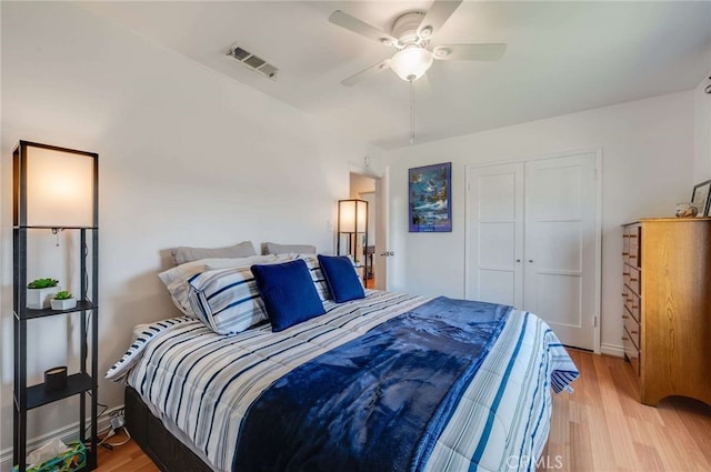 bedroom with light wood-style floors, a closet, visible vents, and a ceiling fan